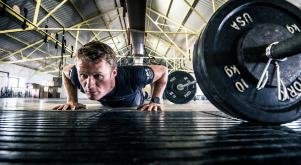 Man performs pushups in a gym while training with high volume instead of high frequency