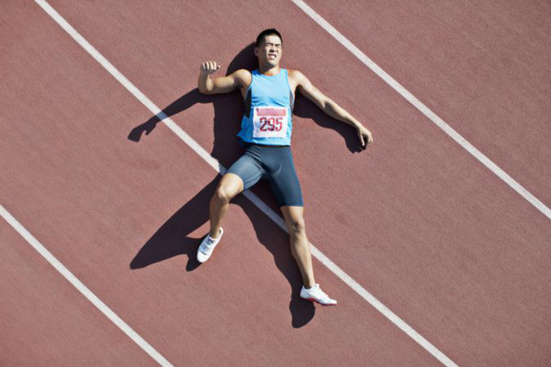 track athlete lies in pain as he waits for the personal trainer to complete his sports hernia diagnosis