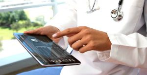 Trained specialist wearing a white lab coat uses physical therapy software for emr and billing to track and manage patient documentation