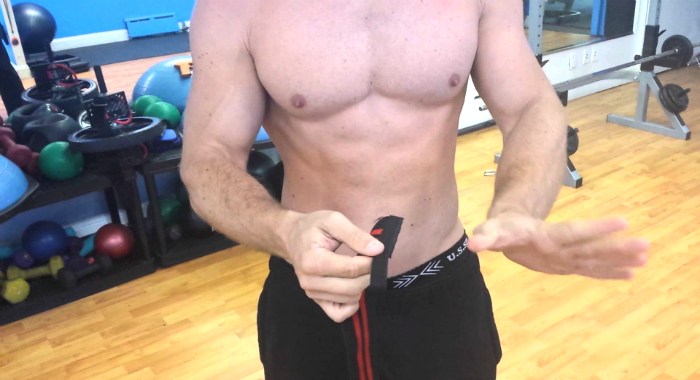 Man puts on powerlifting wrist wraps before an upper-body workout at the gym