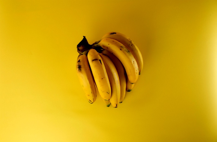 Handful of bananas used in a powerlifting meal plan sitting on a yellow table
