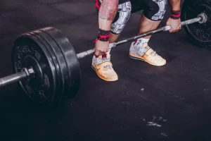 A man holding on to a barbell preforming a deadlift.