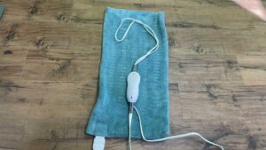 A heating pad with the chord in the shape of a question mark to symbolize whether or not heating pads are good for weight loss.