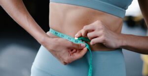 A woman measuring her waistline after figuring out how to lose weight in a few hours.