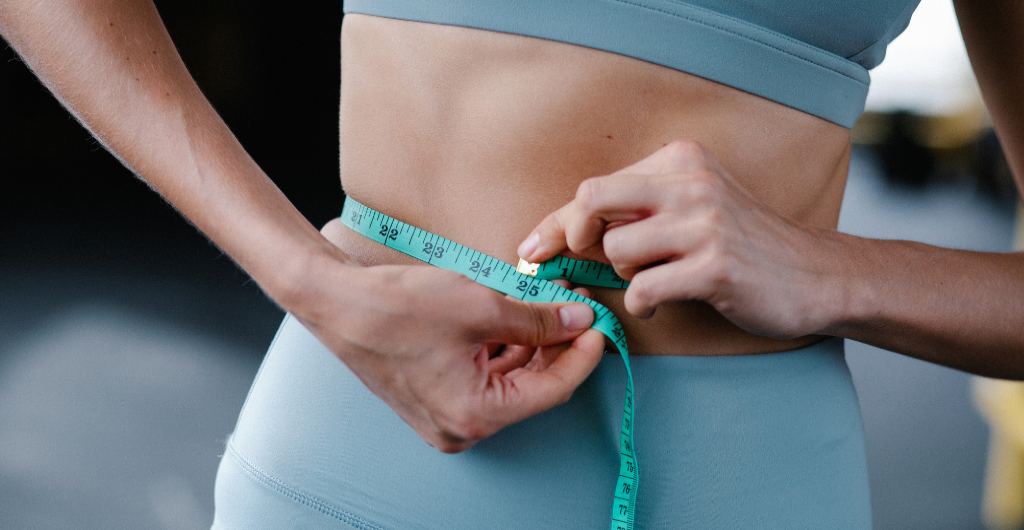 A woman measures her waistline after discovering how to lose weight in just a few hours.