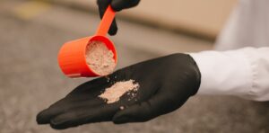 A person is pouring a scoop of herbalife protein powder into their hand to examine it's effectiveness.
