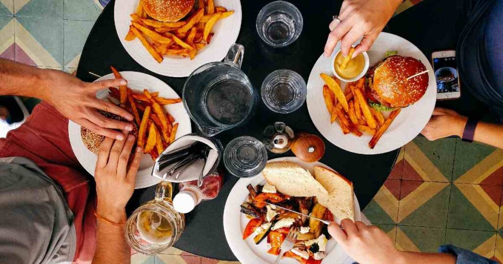 A group of people eating greasy and sugary food at a restaurant.