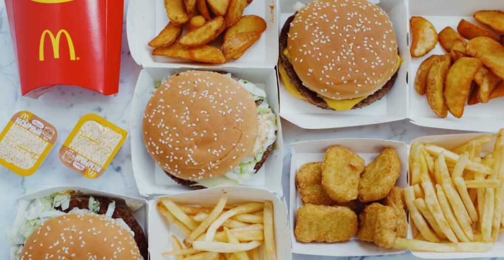 Junk food from McDonald's fast-food chain containing french fries, dipping sauce, chicken nuggets, and burgers.