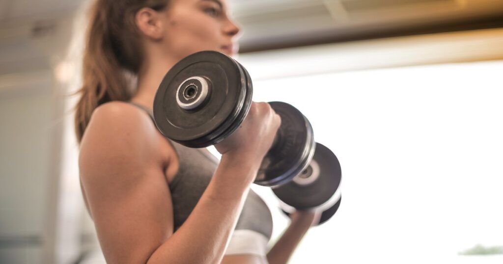 A woman is performing a bicep curl with dumbbells. 