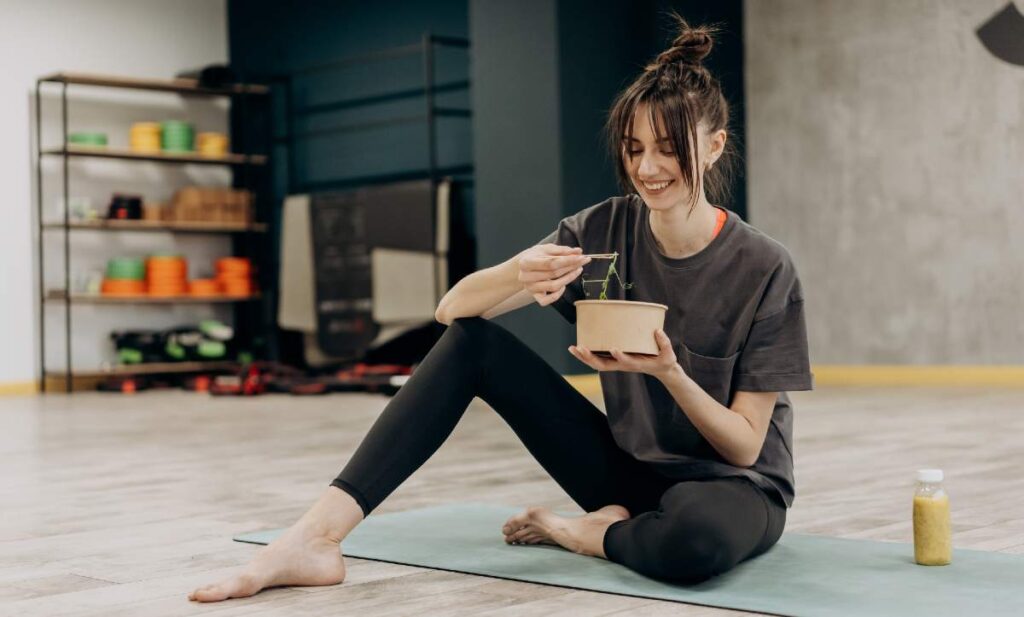 A woman eating healthy greens while sitting.