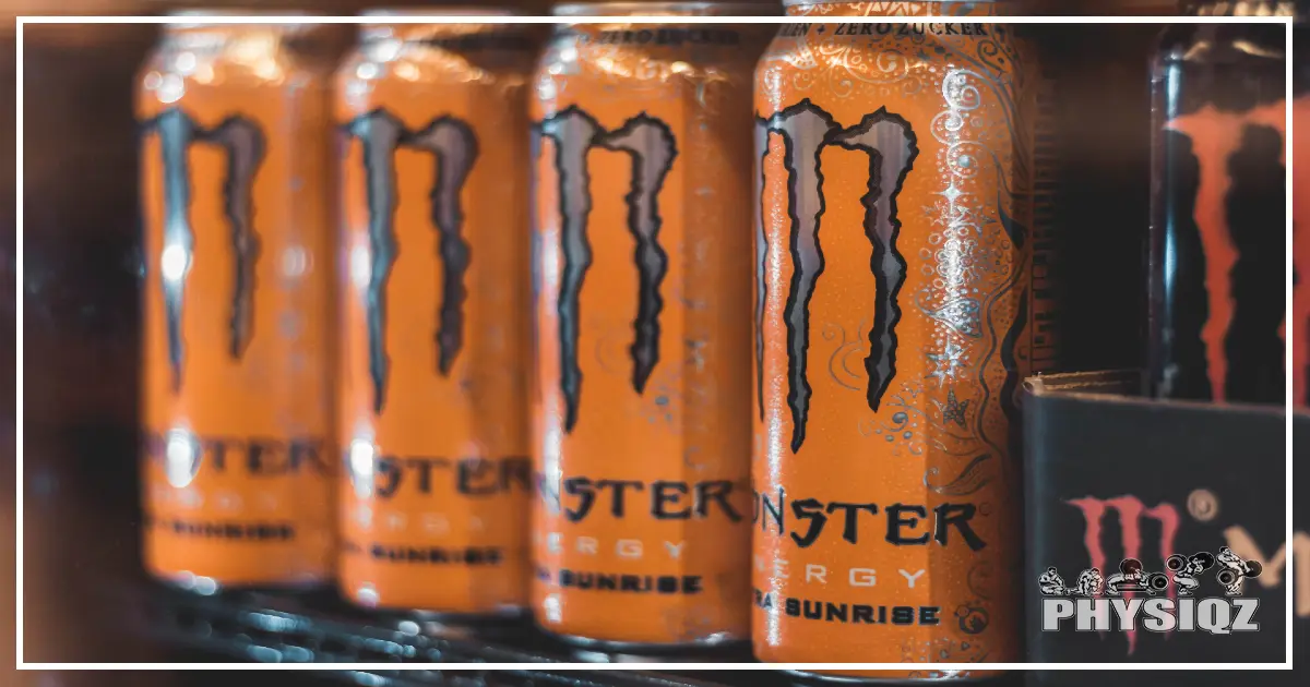 Four orange cans of Monster energy drink displayed orderly.