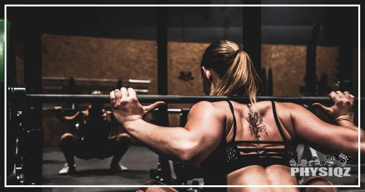 A woman performing a barbell squat to work on building muscle and body recomposition through weigh lifting. 