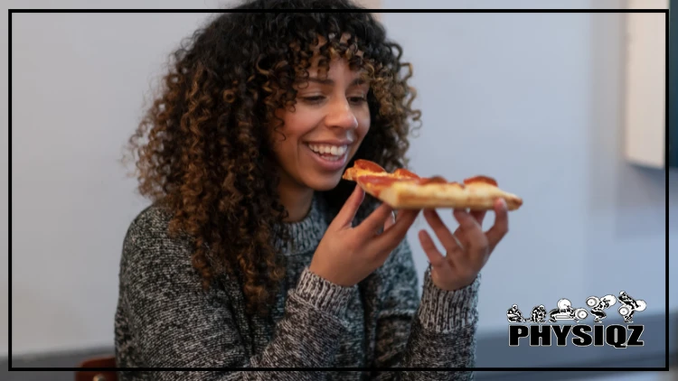 A woman with brunette and curly hair is eating a slice of pepperoni pizza as she asks herself, "Can you eat anything on a calorie deficit?" or "Does it matter what I eat as long as I count calories?"