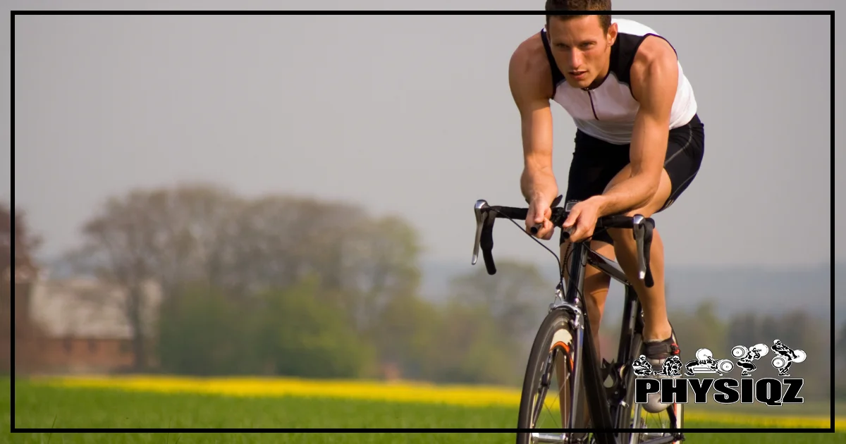 A man is pedaling a road bike out in the country hills with green grass behind him and he's wearing a black and white sports tank top.