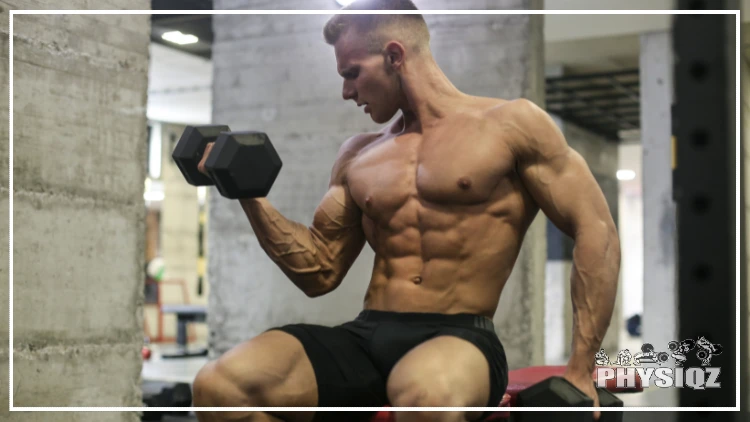 Shirtless inside an industrial building with concrete walls, a man executes a slow eccentric movement to strengthen his muscles while performing a bicep curl.