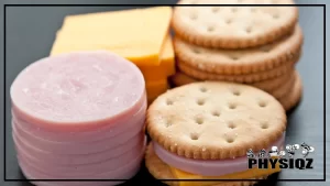 Close-up photo of a children's lunchables pack, unwrapped on a black kitchen table with crackers, meat, and cheese stacked side by side in the correct combination of calories ready to eat after researching are lunchables good for weight loss.