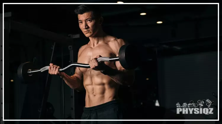 A lean Chinese man is performing an EZ bar curl with a serious look on his face and with s smith machine in the background. 