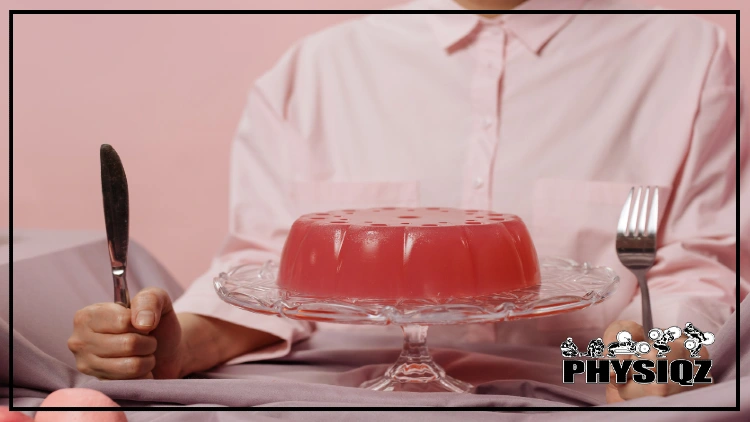 Man wearing a white button-up shirt sits behind a sugar free jello cake with a knife and fork in his hand waiting to eat until he knows how many carbs in sugar free jello are allowed while on a weight loss diet.