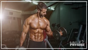A tan, muscular guy is standing in a gym with a bench press rack in the background as he performs a dumbbell curl that's programmed into his progressive overload workout plan