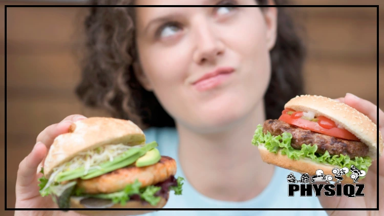 A woman in a blue shirt and a curious facial expression is holding a chicken burger with tomatoes and avocados on a potato bun in her right hand, and in her left hand she's holding a thick charred beef burger with tomatoes above the patty and lettuce below the patty. 