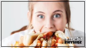 A woman with strawberry blonde hair and blue eyes is wondering "Are hot dogs keto friendly" as she shoves five hot dogs in her mouth at once and there's ketchup and other condiments leaking out of the buns.