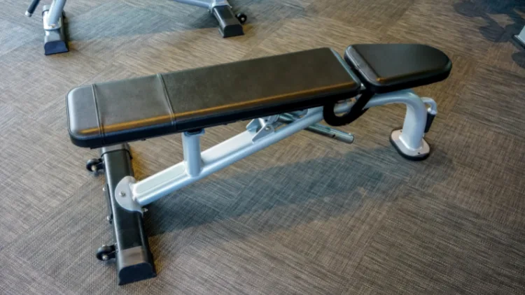 An adjustable bench in a gym with wood patterned floor.