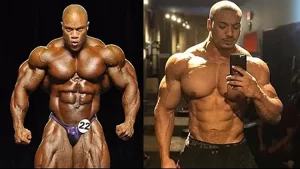 A powerlifter physique vs bodybuilder physique is compared by having Phil Heath, a professional bodybuilder, on the left wearing purple bottoms that has a #22 pin on them since he's on stage and flexing his large, proportionate and defined muscles but on the right is Larry Wheels, a professional powerlifter taking a mirror selfie that shows he's muscular, but has a blocky torso, less than desirable proportions, and isn't nearly as lean as Phil.