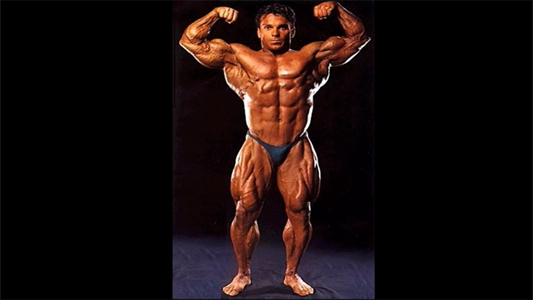 Rich Gaspari is performing a font double bicep pose at a lean body mass that reveals his uneven nipples and chest muscles. 