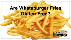 A man with a black baseball cap is sitting next to a window in a Whataburger restaurant and is wearing a black hat and blue t shirt as he holds an orange and white striped Whataburger French fry container while asking himself "Are Whataburger fries gluten free?".
