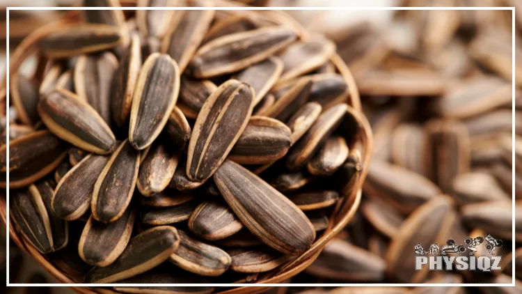 A small woven bowl is filled with sunflower seeds and laying on a bed of more sunflower seeds.