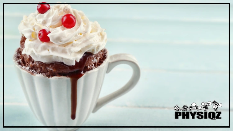 A white mug is filled with hot chocolate that is spilling over the edge and topped with whipped cream and red maraschino cherries.