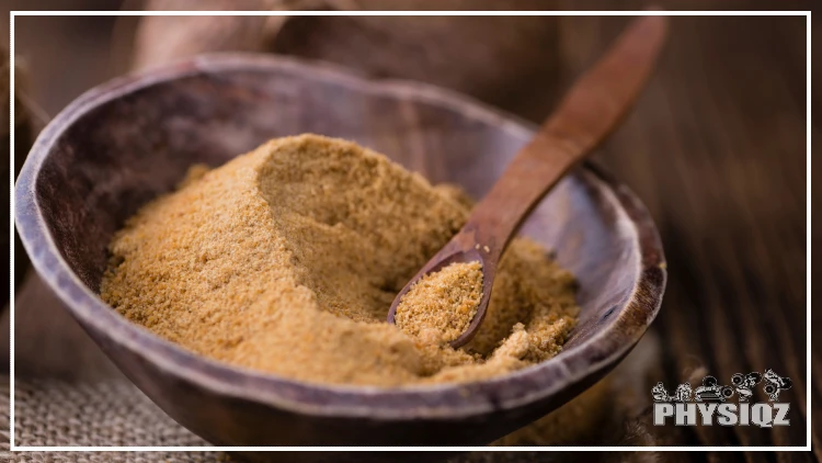 A wooden bowl with a wooden spoon, filled with coconut sugar.