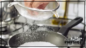 A person is making tapioca and wondering, 'Is cassava flour keto-friendly?' while sifting cassava flour using a steel sifter onto a black pot below.