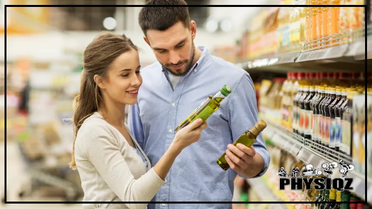 In a grocery store aisle, a woman in a white long-sleeved shirt and a man in a light blue button-up are examining the labels on olive oil bottles to see if they are suitable for a keto diet.