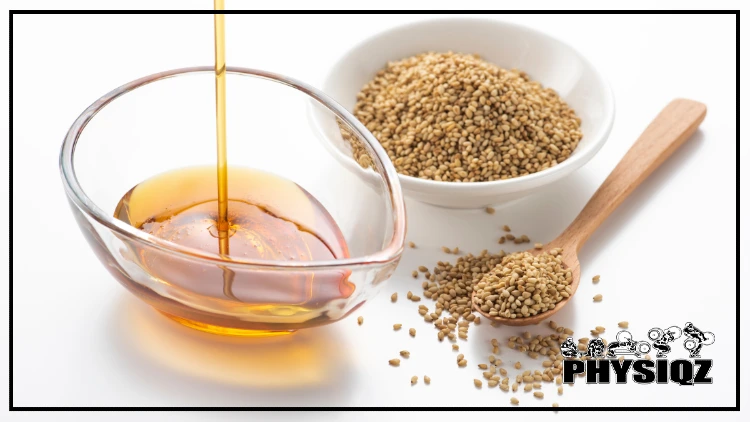 As a small glass bowl shaped like a droplet fills with golden sesame seed oil, sitting next to a white bowl of raw sesame seeds and a wooden spoon, many dieters wonder if they can use sesame oil on a keto diet.