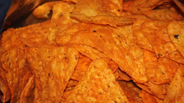 A close up of an inside of a snack showing orange triangle-shaped chips.