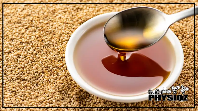 A small white saucer filled with sesame seed oil is being stirred by a spoon while sitting on a bed of sesame seeds. 