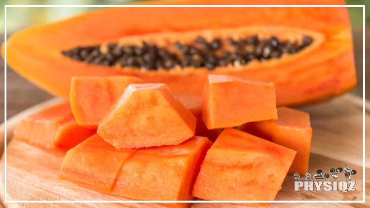 A papaya is sliced and the its seeds are showing with some pieces of the fruit diced up. 