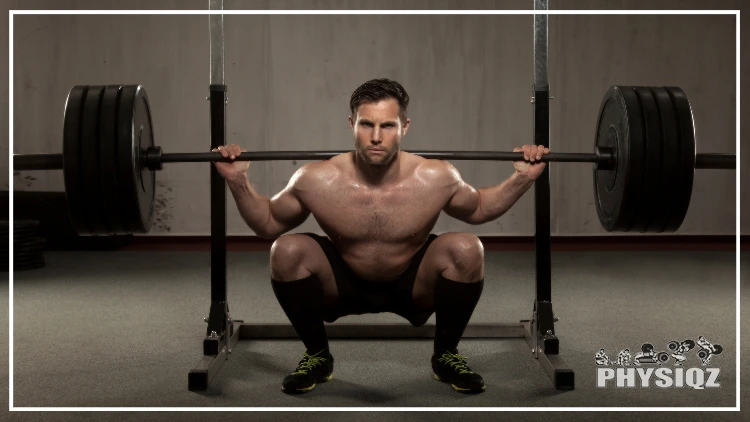 A topless powerlifter, wearing a black short, shoes and socks is doing a deep squat using a barbell with 4 weighted plates and wonders "Is 405 squat good weight, or is it just okay?", in a dimly lit gym with concrete wall and floor.