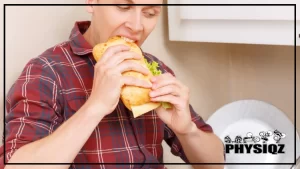 A main wearing a red flannel eating a sandwich while looking down, browsing how to order from the Potbelly gluten free menu for his next order.
