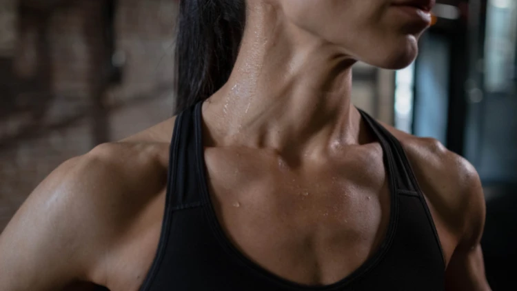 A close up of woman sweating wearing a black tank top.