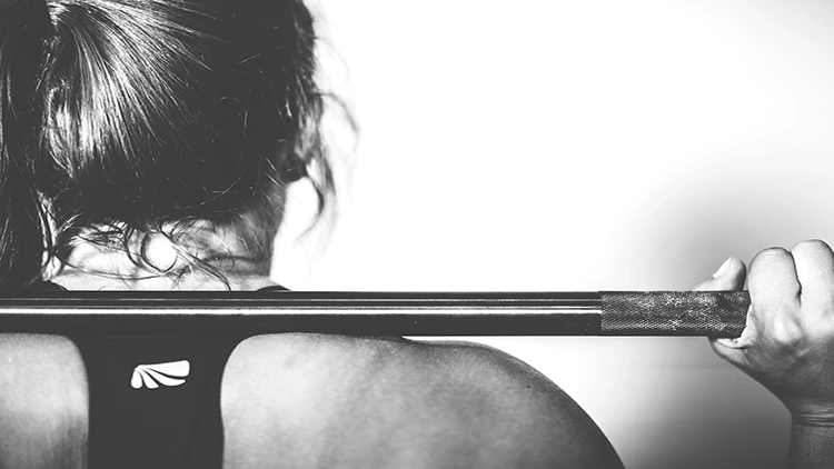 A black and white close up photo of a woman lifting a barbell.