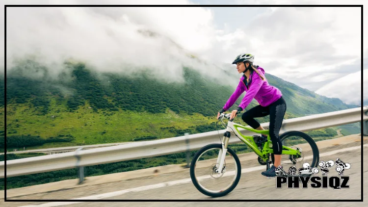 A woman in a helmet and purple jacket cycling with determination and a serene expression against a backdrop of majestic mountains and cloudy skies.