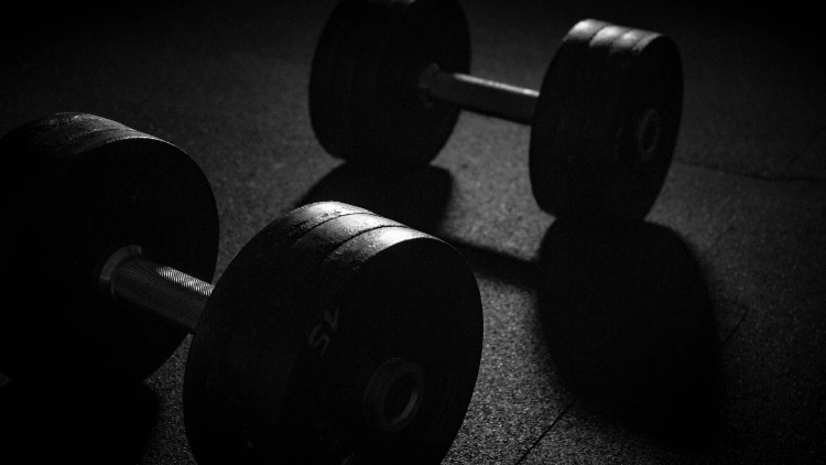 A pair of dumbbells on the floor in a dimly lit studio.