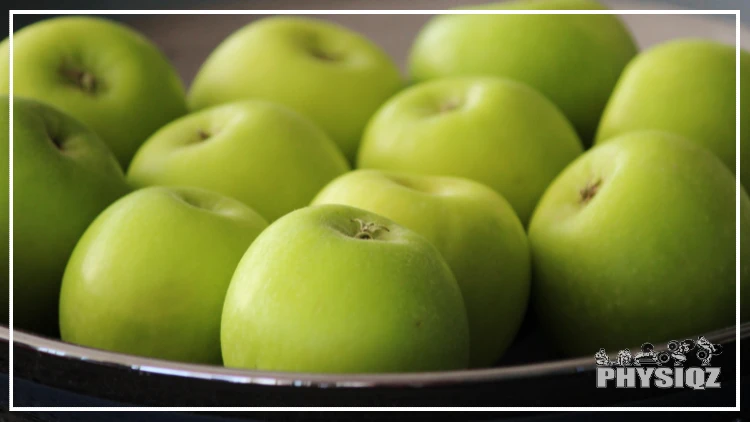 Eleven green apples with speckles on it and the stims pitted are resting inside a silver bowl which leads some dieters to question if a green apple is keto or not.