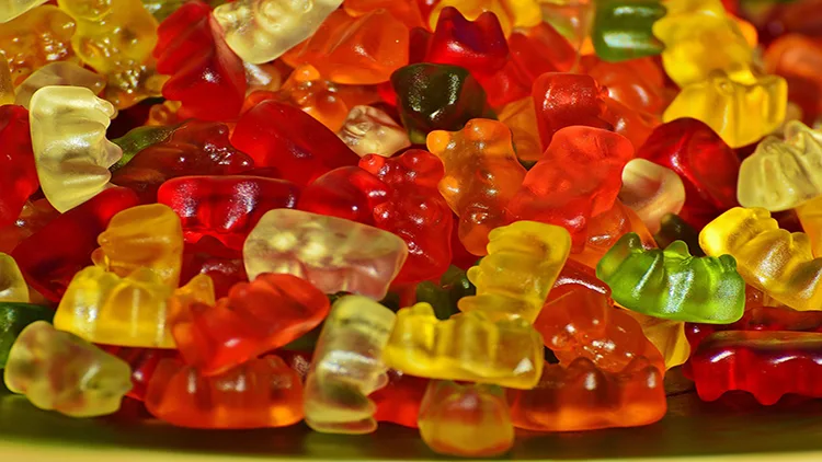 A bunch of gummy bears in different colors such as red, yellow and green.