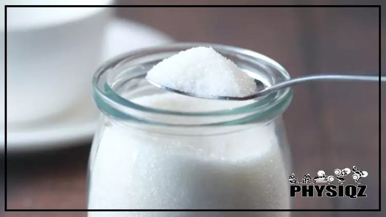 A small glass jar full of white crystalline powder makes some question "is dextrose keto" and it's resting on top of a wooden table with a plate and cup in the background.