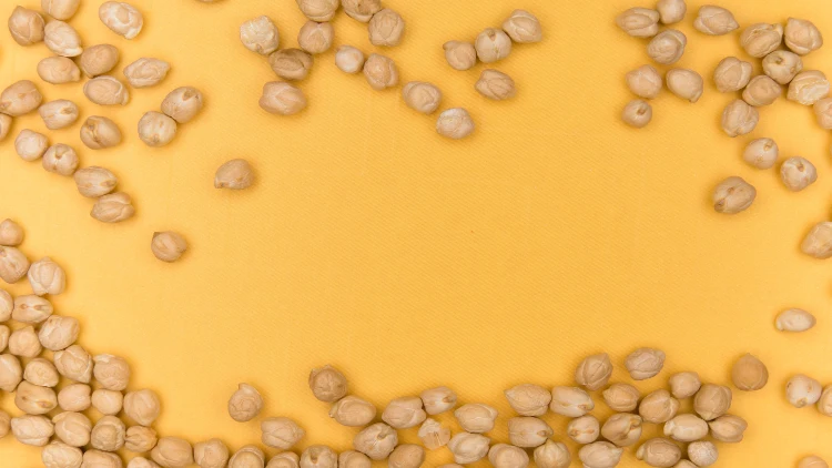 A bunch of chickpeas scattered against an orange background.