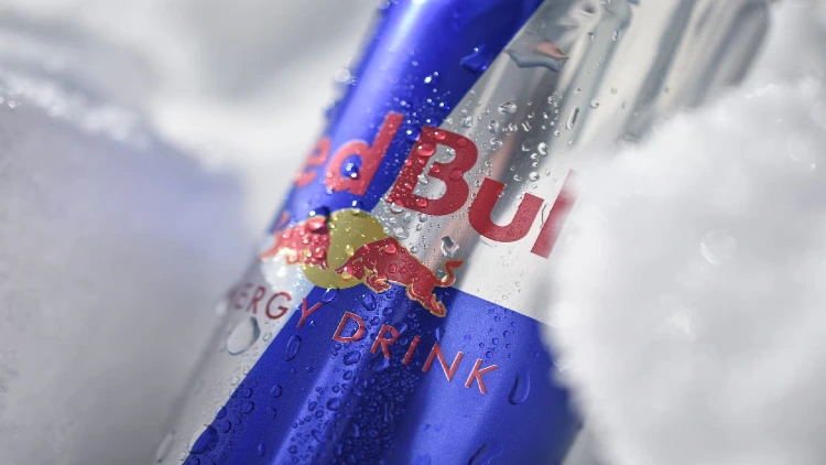 A cold RedBull energy drink can with droplets of moisture on the surface, prominently featuring the brand name 'RedBull' in bold letters on a vibrant blue and silver background.