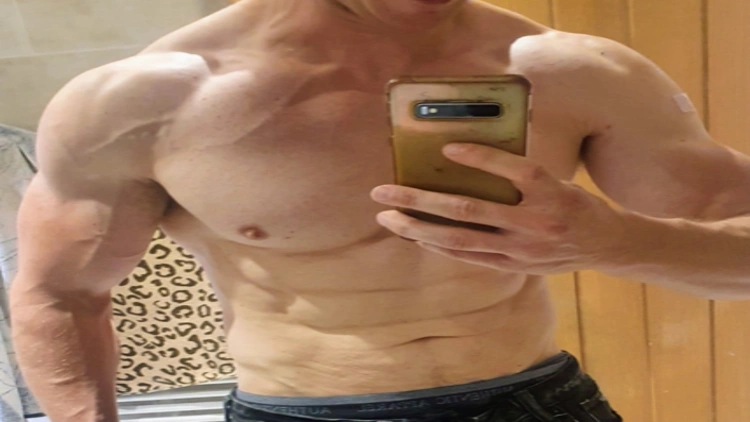 Mirror selfie of derek's muscular body transformation after using sermorelin, with visible abs, toned chest, and biceps.